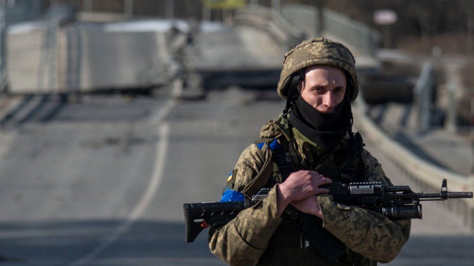 A Ukrainian soldier walks near a destroyed bridge in the Sumy region