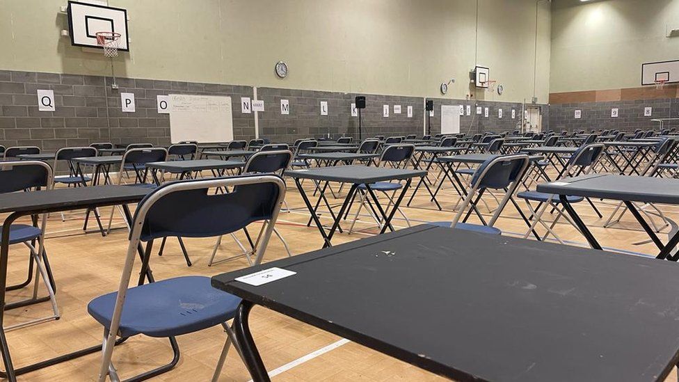 A sports hall filled with desks for exams
