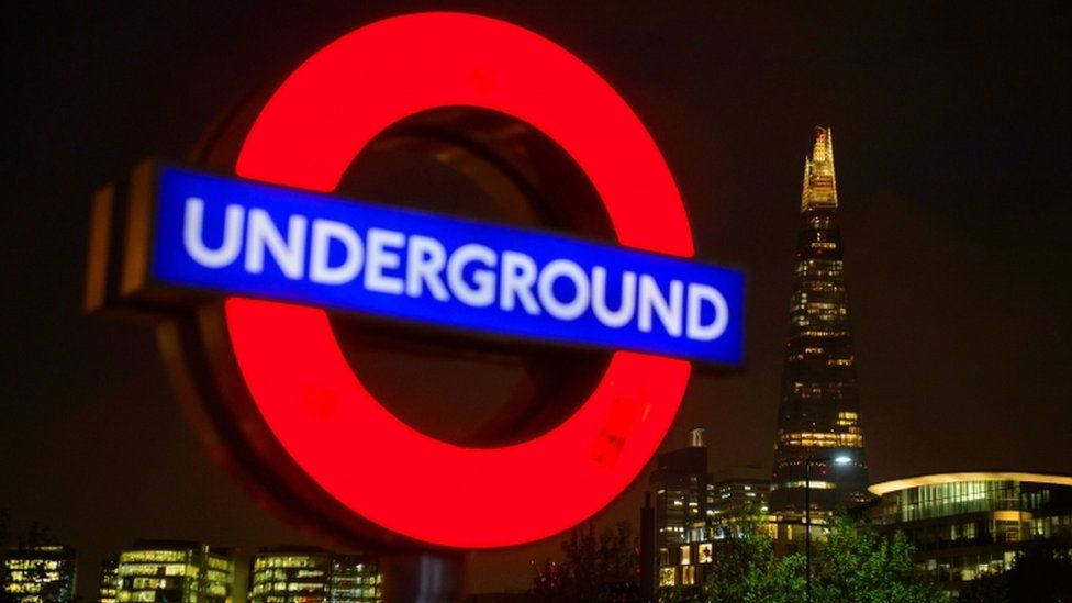 A London Underground sign is seen alongside the Shard at night