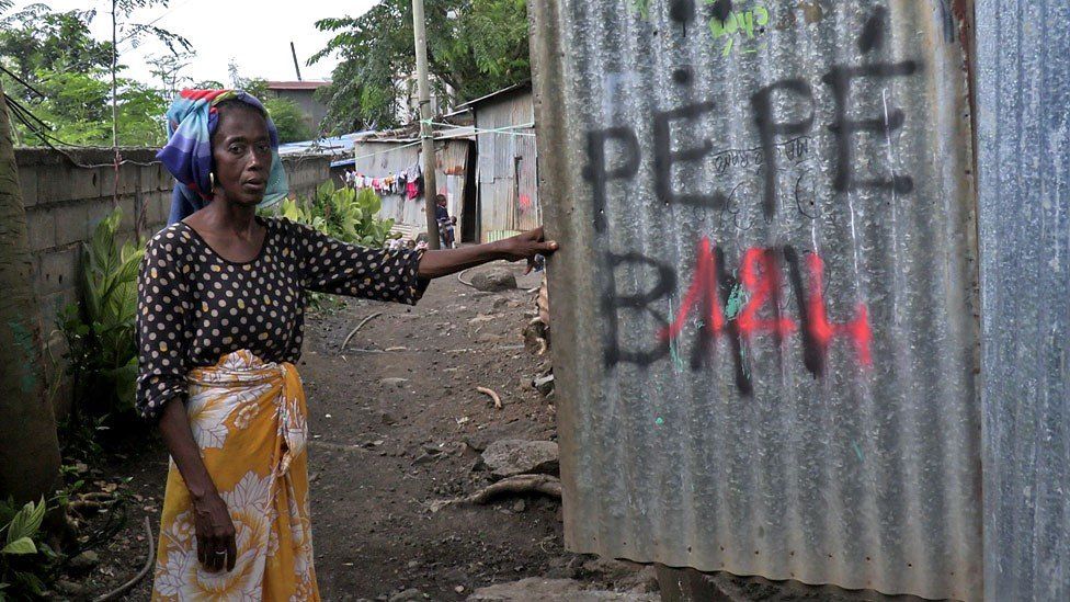 Fatima pointing at a 'tag' sprayed on her home