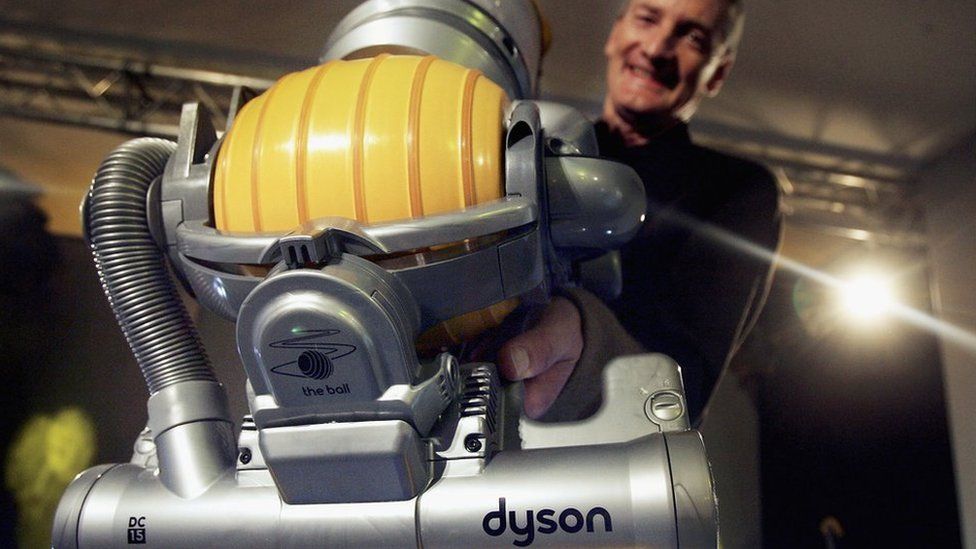Sir James Dyson holds up a vacuum cleaner