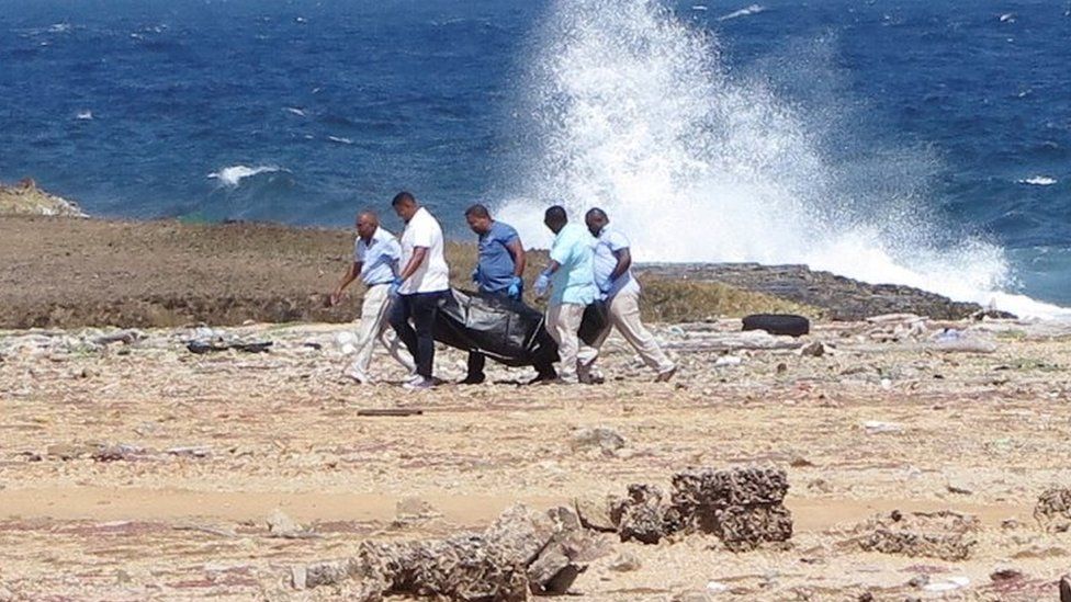 Forensic workers carry a bag containing the body of a person who was found at the shore, near Willemstad, Curacao January 10, 2018.