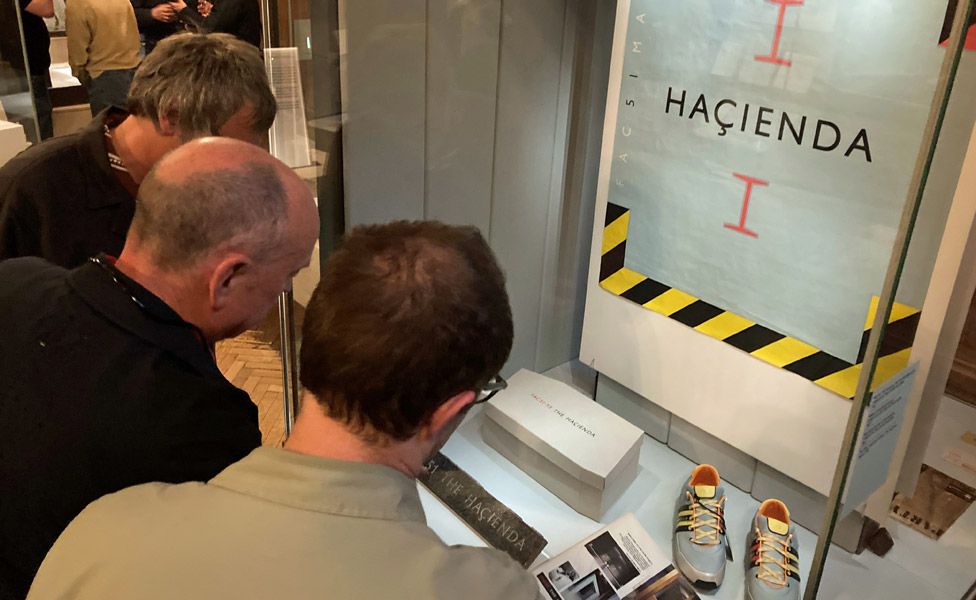 People looking at a Hacienda poster at the British Pop Archive exhibition at the John Rylands Library in Manchester