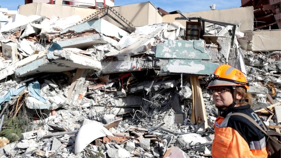 A member of emergency services stands next to a collapsed building in the Albanian town of Durres