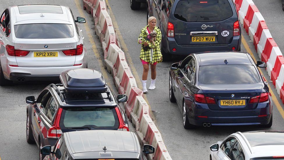 A woman carries her dog amid gridlocked traffic