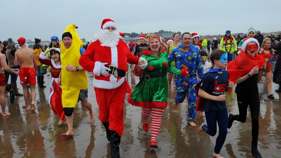 People in fancy dress running into the sea
