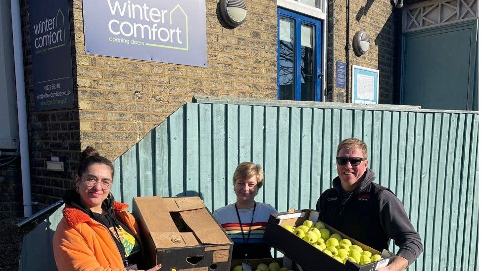 Boxes of apples being held by people outside the charity Winter Comfort