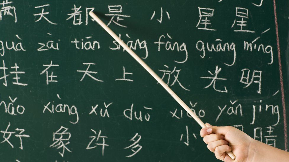 Girl pointing at blackboard in a Chinese lesson