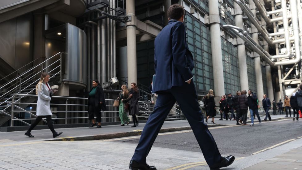 Man walks past Lloyd's of London building in the City of London