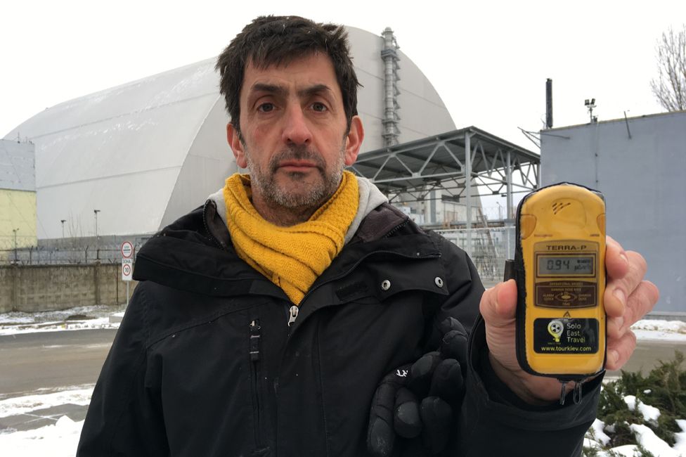 Justin Rowlatt holding a Geiger counter, close to the sarcophagus