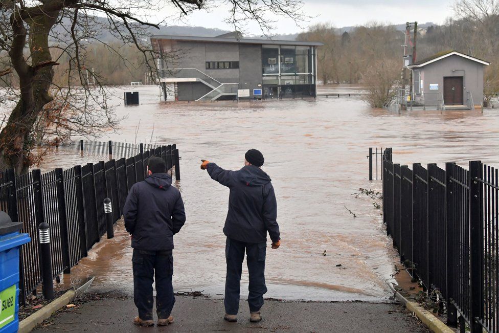 Two men view a flooded area of the sports pavilion at Monmouth School, Monmouth.