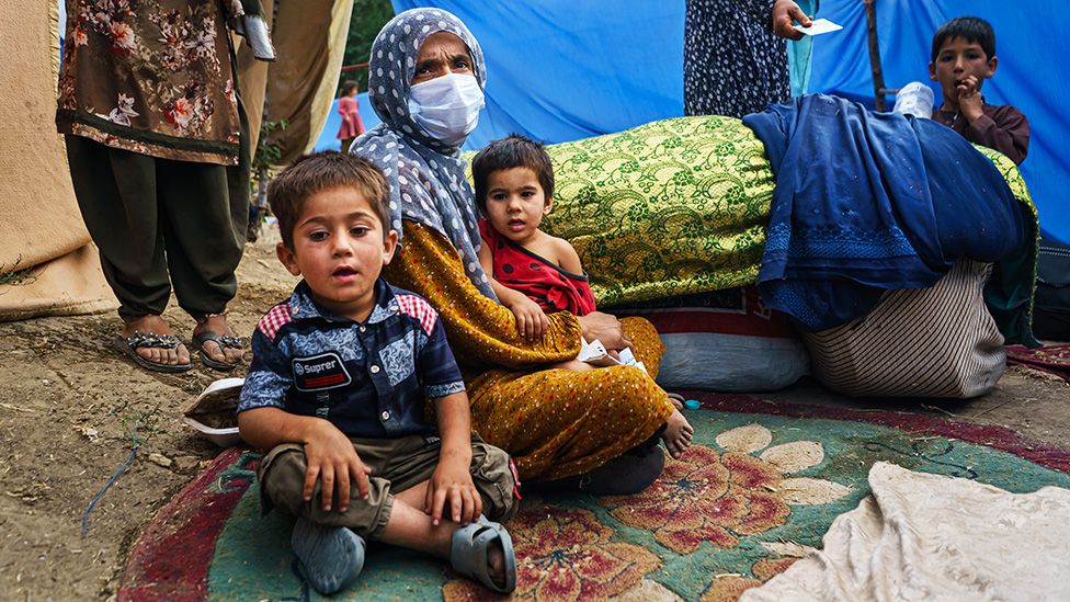 Афганская семья, бежавшая от боевых действий в провинции Кундуз, сидит во временном лагере в парке Хаса-э-Аваль в Кабуле, Афганистан - 14 августа 2021 г.