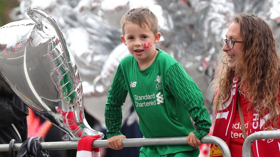 A young fan waits in anticipation for the parade with a woman watching him