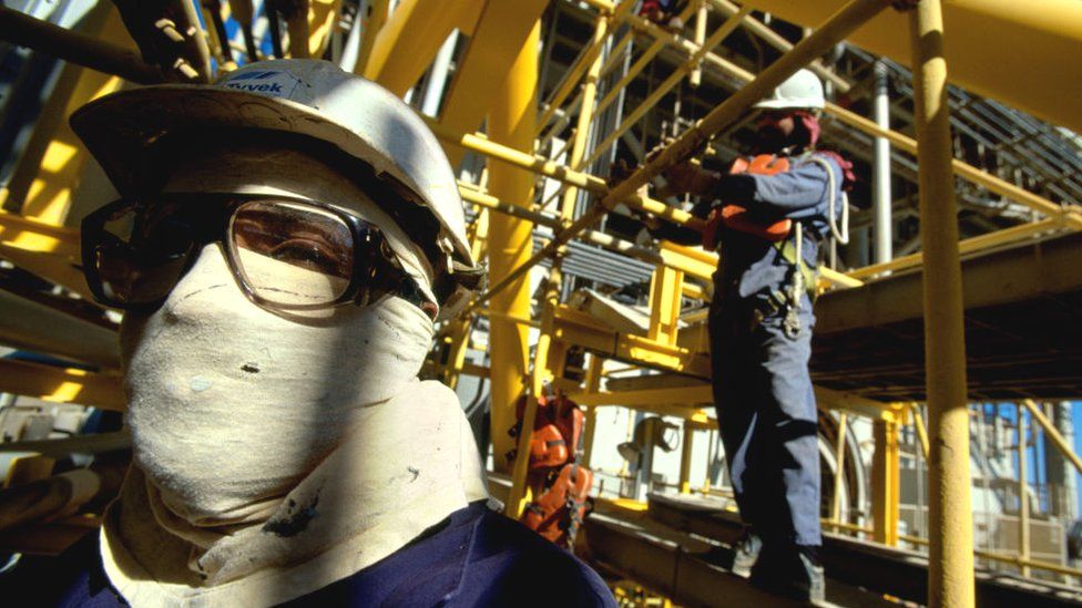 Рабочий стоит в технической зоне саудовской национальной нефтяной компании Aramco в Саудовской Аравии.