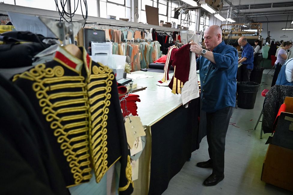 A worker inspects a Household Cavalry gold coat uniform to be worn during the Coronation