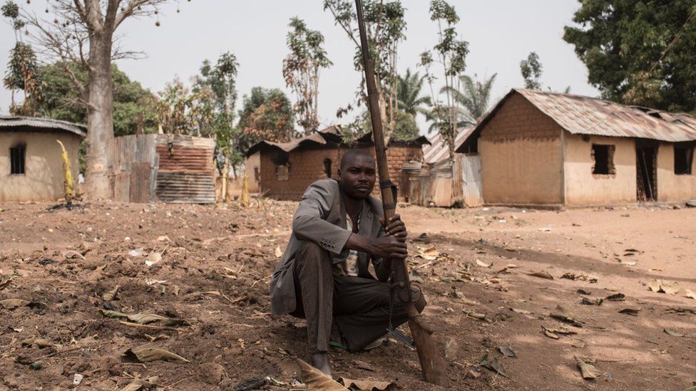 A vigilante sits on the ground with his gun in the village of Bakin Kogi, in Kaduna state, northwest Nigeria, that was recently attacked by suspected Fulani herdsmen