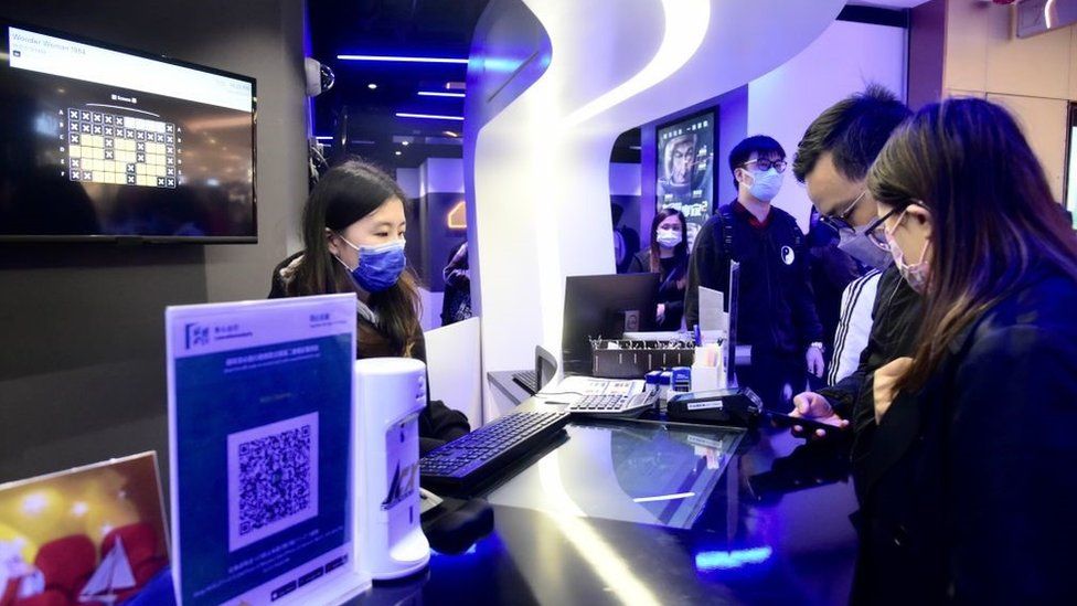 Кинозрители покупают билеты в кинотеатре во время его открытия 18 февраля 2021 года в Гонконге