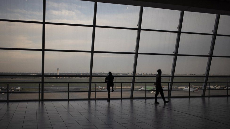 Travellers look out onto the tarmac of the OR Thambo International Airport as restrictions on international flights from South Africa start to take effect in Johannesburg, South Africa, on 30 November 2021