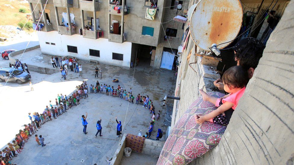 Syrian refugee children form a circle as volunteers entertain them inside a housing compound in Sidon, Lebanon (12 June 2016)