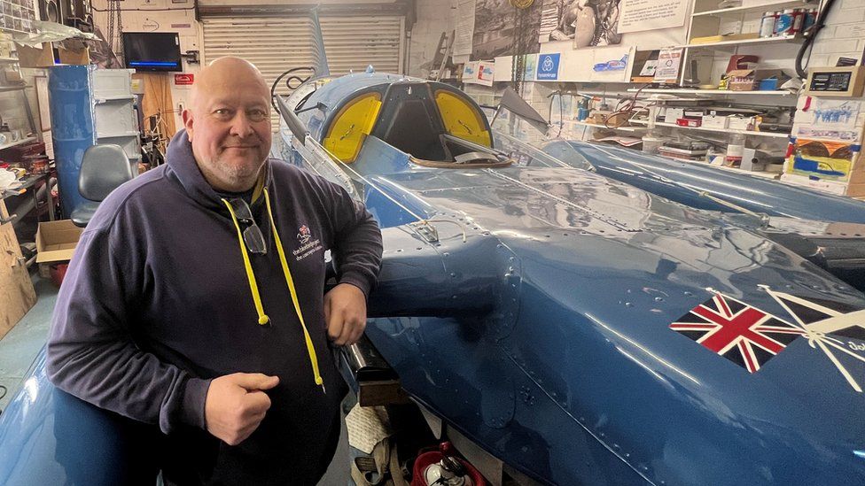 Bill Smith standing next to Bluebird in his North Shields workshop
