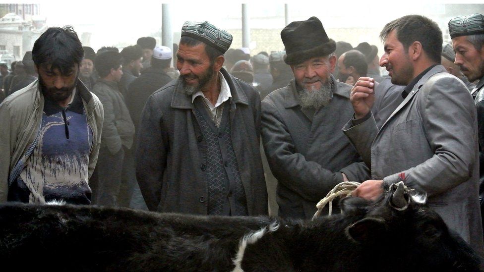 A picture taken on 7 November 2013 showing Uighur men gathering at a bazaar to sell their live sheep in Hotan, Xinjiang region.