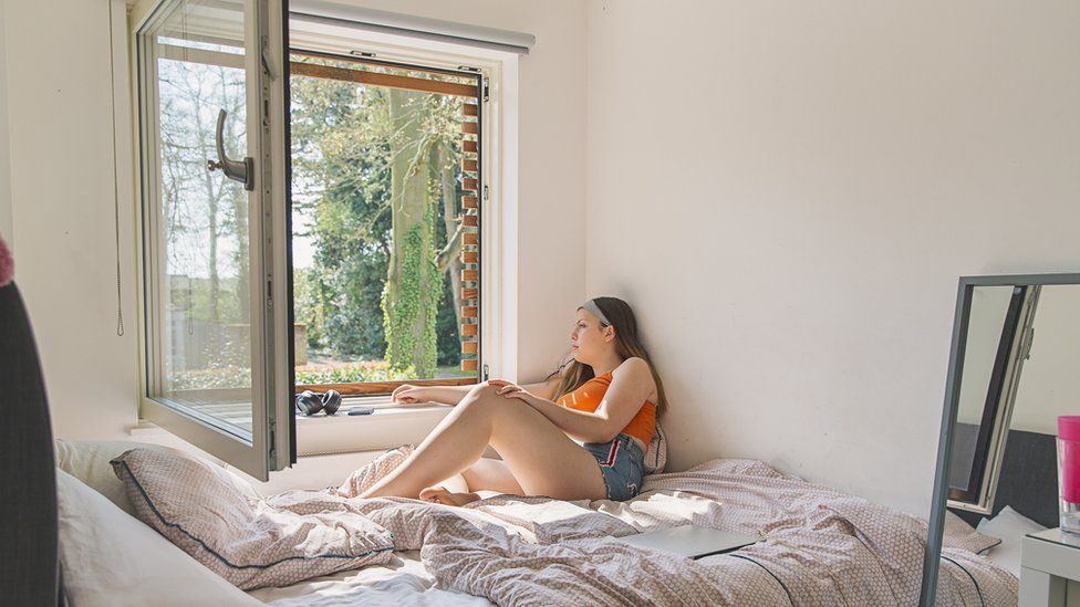 teenage girl looking out of her window - stock photo