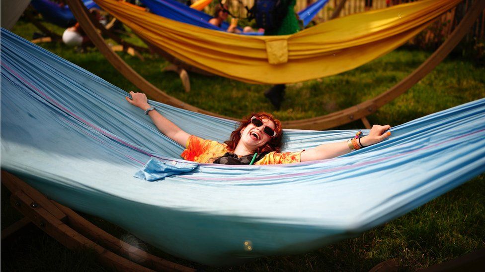 A festival goer relaxes in a hammock at Glastonbury festival