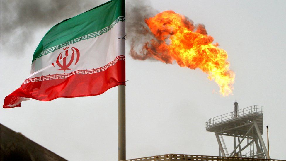 A gas flare on an oil production platform in the Soroush oil fields is seen alongside an Iranian flag in the Persian Gulf, Iran
