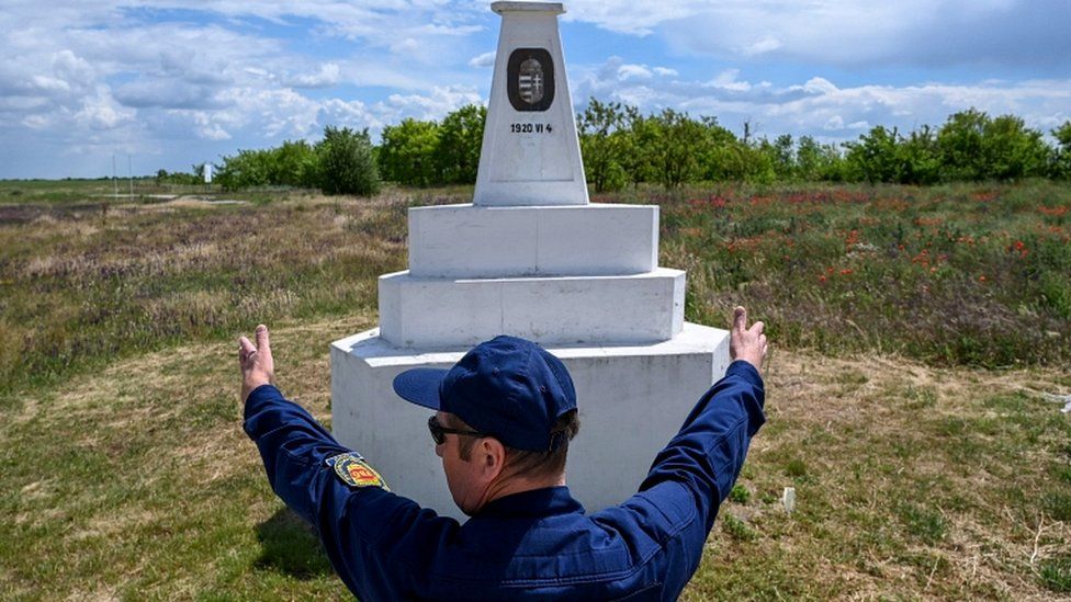 A border guard stands next to triangular stone column marking the spot where the borders of Hungary, Romania, and Serbia meet in Kubekhaza near Szeged on May 25, 2020