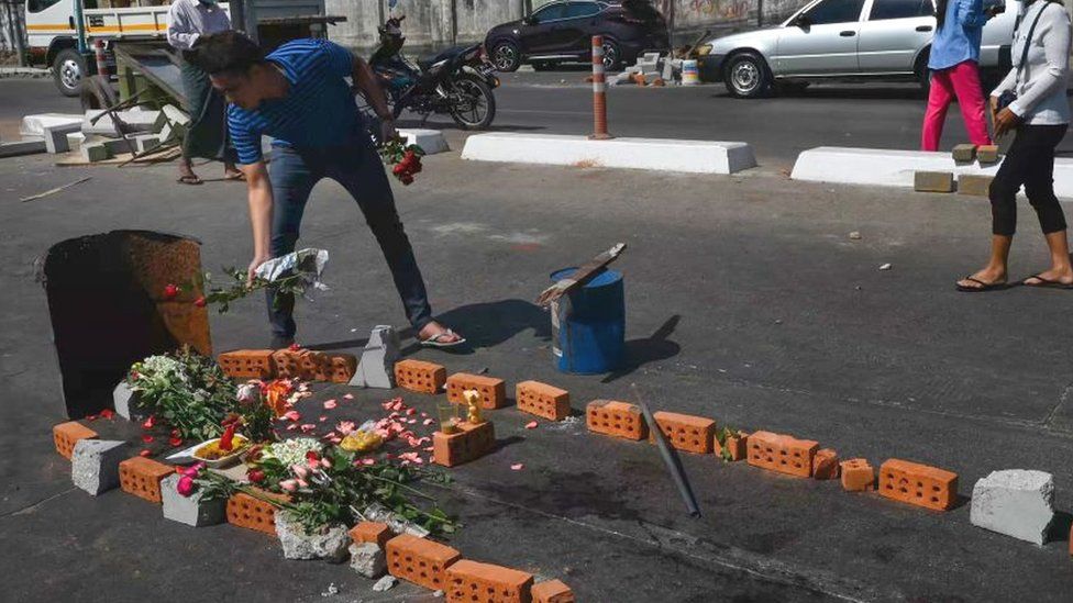 Мужчина возлагает цветы на месте импровизированного мемориала,