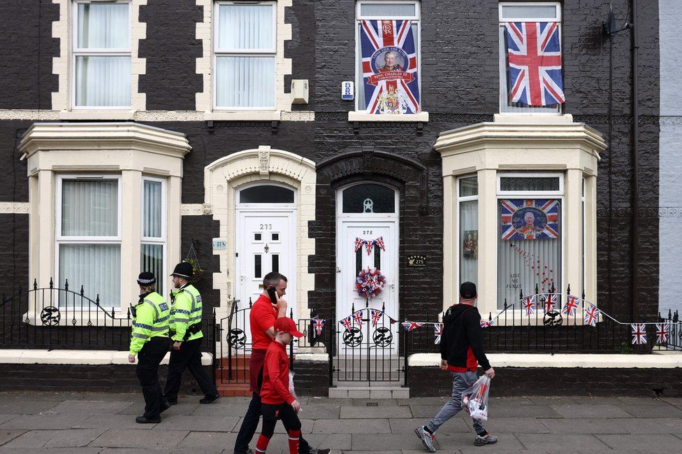 Fans and police officers walk past house with royal memorabilia