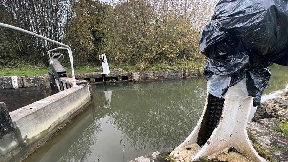 Broken part of a lock on the Kennet and Avon canal marked out of action by being covered by a back bin bag