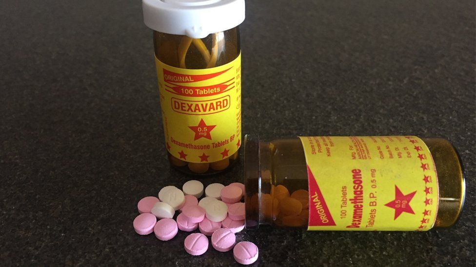 Two plastic bottles containing small pink and white pills.