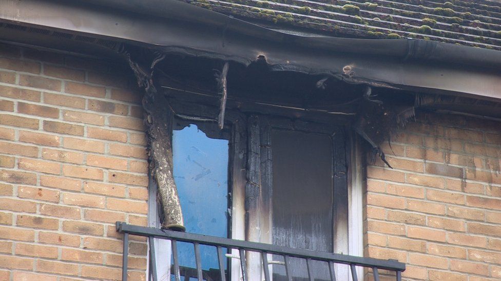 A window frame is blackened from the now-extinguished fire.