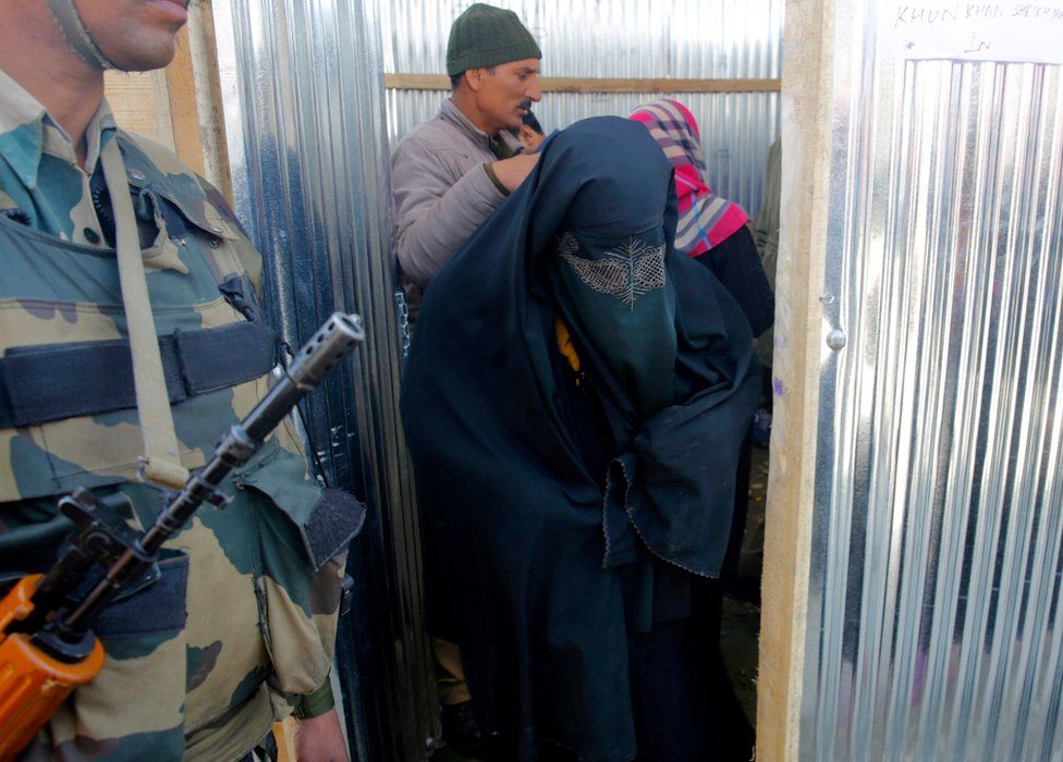 A Kashmiri Muslim woman walks past a paramilitary solider after casting her vote during parliamentary by-elections in Srinagar, the summer capital of Indian Kashmir, 9 April 2017.