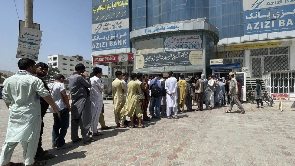 Afghan people line up outside AZIZI Bank to take out cash as the Bank suffers amid money crises in Kabul, Afghanistan, on August 15, 2021.