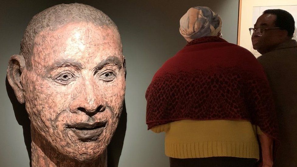 People standing by Brown Painted Head by John Davies