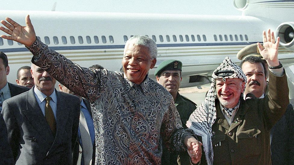 Palestinian Authority President Yasser Arafat (r) and the former South African President Nelson Mandela (l) wave to a cheering crowds during their meeting at Gaza International Airport in Rafah - 19 October 1999