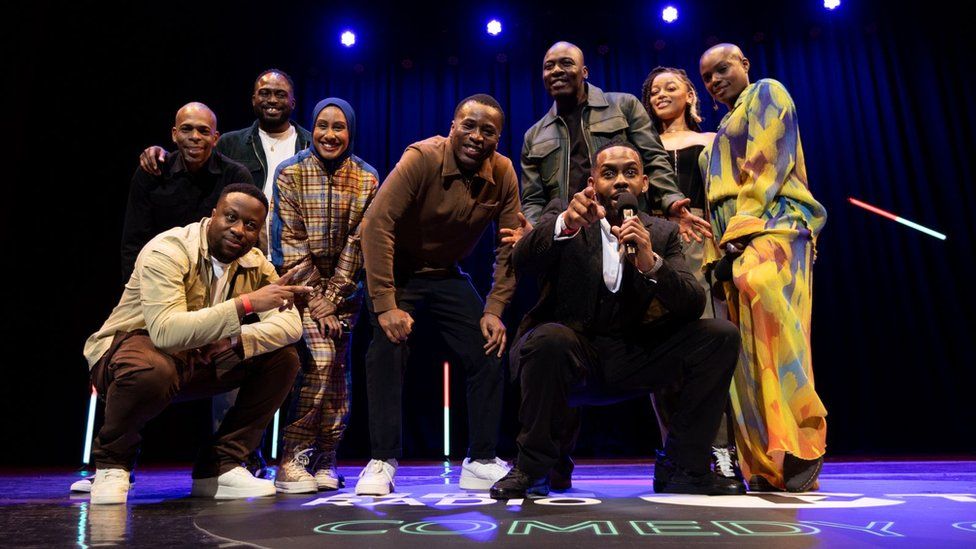 The comedians who performed for the BBC IXtra Comedy Gala: Thanyia Moore, Kane Brown, Babatunde Aléshé, Slim, Gbemi Oladipo (Bemi), Kyrah Gray, Ola Labib and Michael Odewale. The acts are grouped together on stage, smiling at the camera