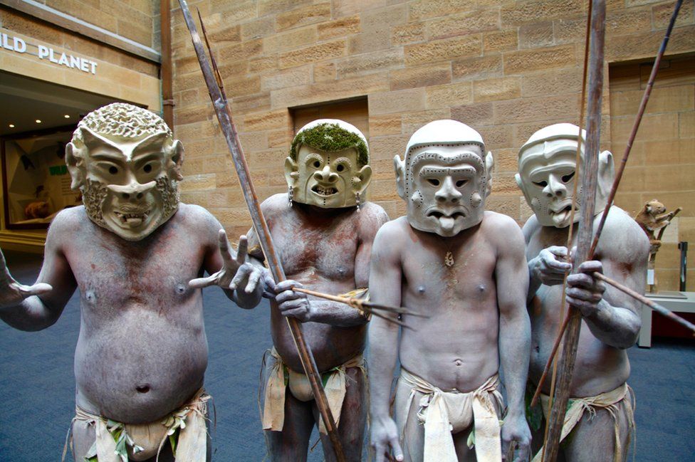 The four mud men who have travelled to Sydney - wearing their scary clay masks with painted white bodies and holding bows and arrows