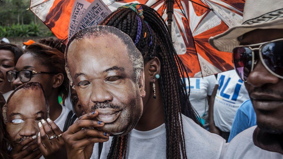 A supporter of Gabon's President Ali Bongo Ondimba wears a mask with the face of the President at an electoral rally in Moanda on August 23, 2016