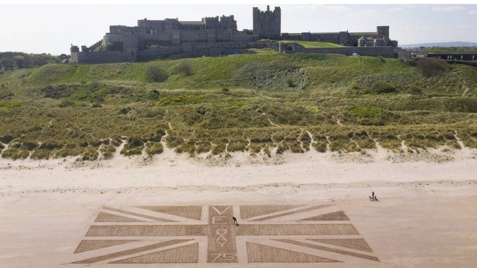 A giant union flag created with footprints on the beach beneath Bamburgh castle in Northumberland