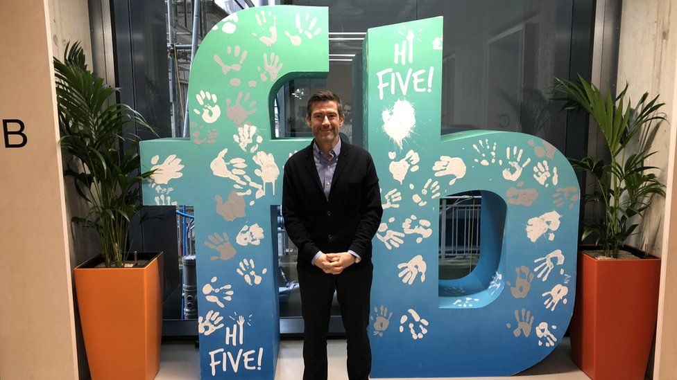 Steve Hatch standing in front of the Facebook logo