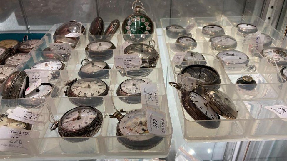 Dozens of pocket watches on a shelf