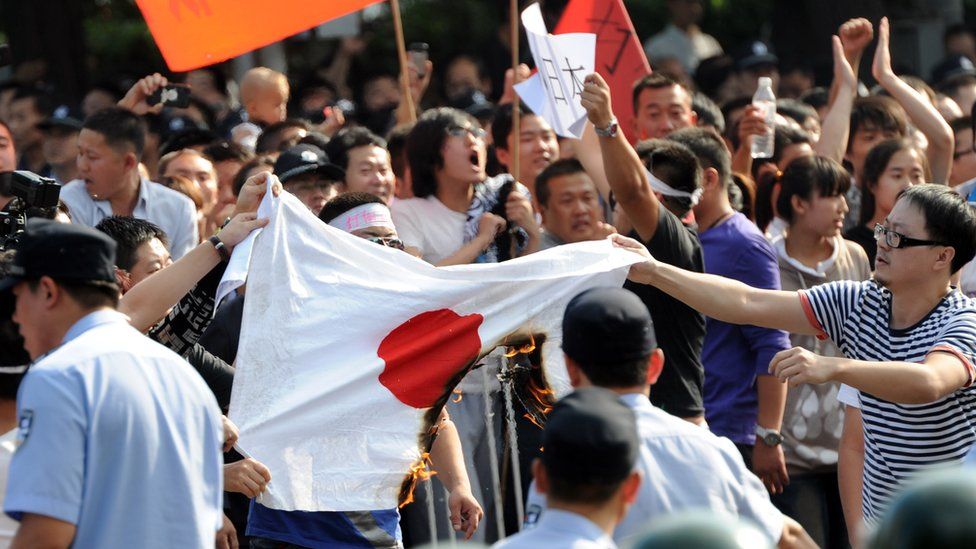 Chinese protesters burn a Japanese national flag during an anti-Japanese protest over the Diaoyu islands issue, known as the Senkaku islands in Japanese, outside the Japanese Embassy in Beijing on September 15, 2012