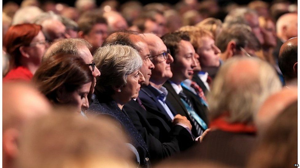 Theresa May listening to Philip Hammond speaking