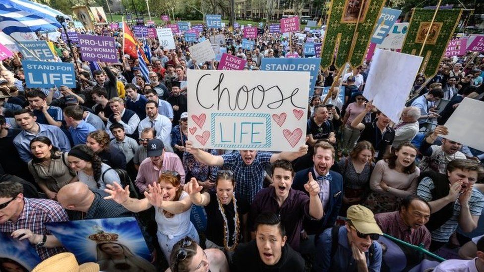 A group of pro-life supporters hold placards including "choose life"