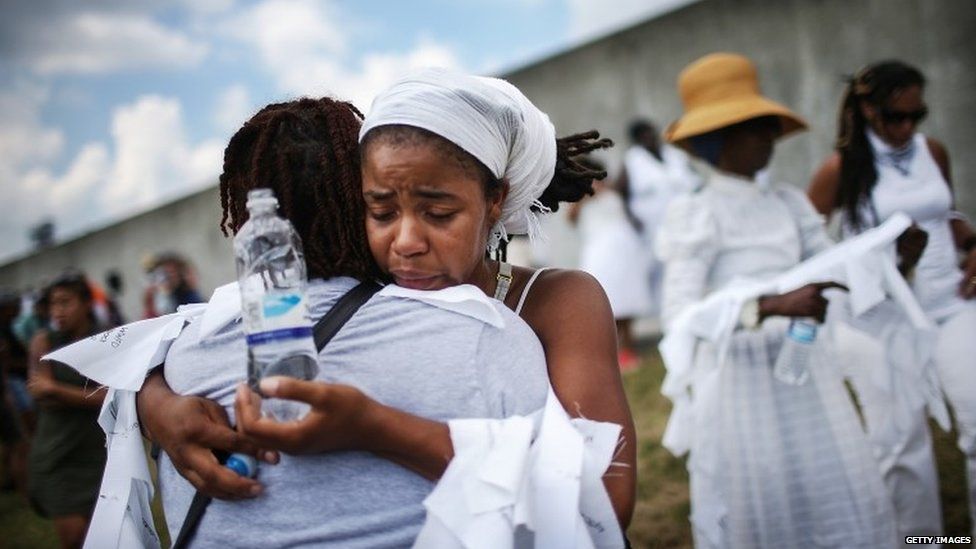 Savannah Shange hugs a woman in front of the repaired levee wall in the Lower Ninth Ward