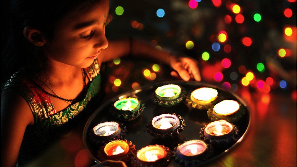 Girl holding lit diyas