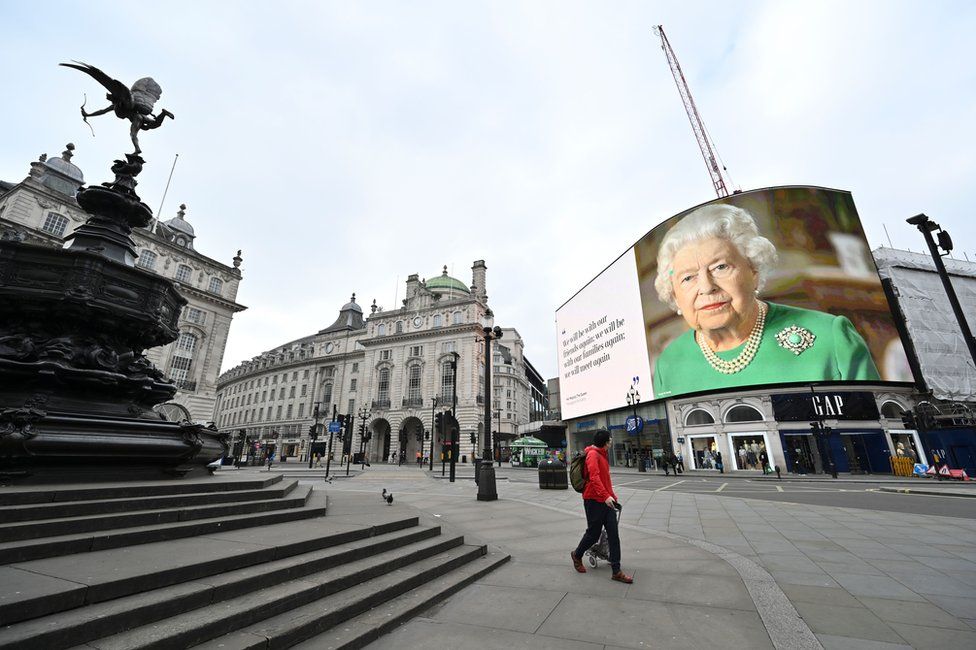 A billboard screen in Picadilly Circus shows an image of the Queen
